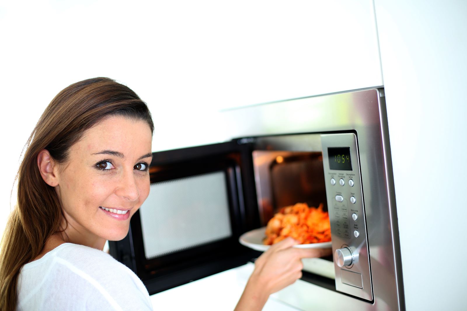 Woman putting plate in microwave oven